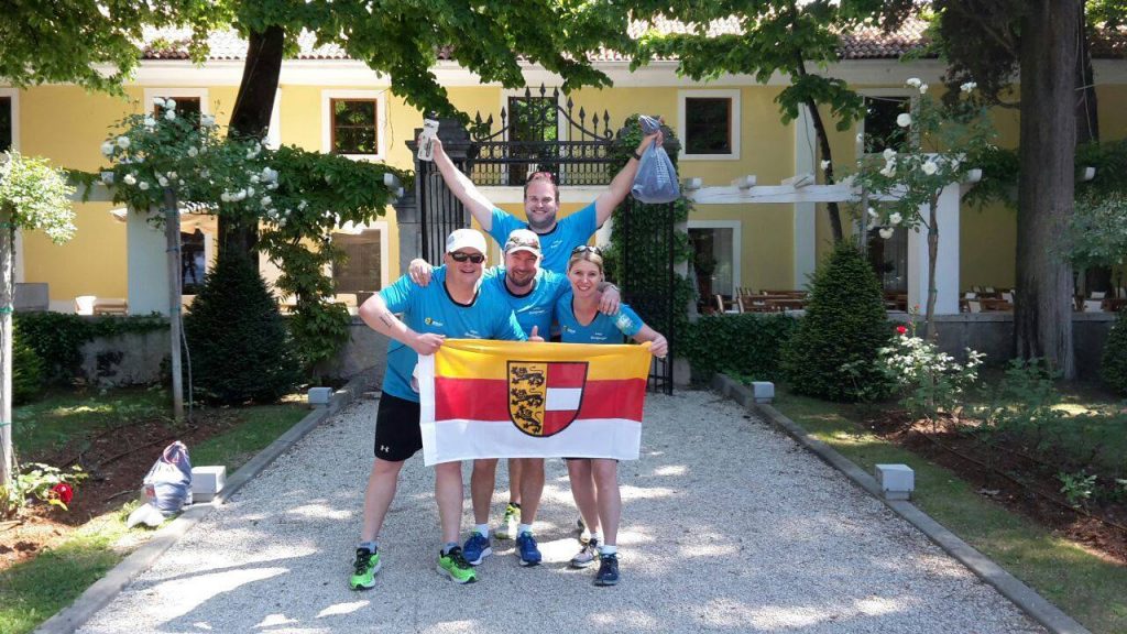 Vier Menschen/Team mit Kärnten Flagge