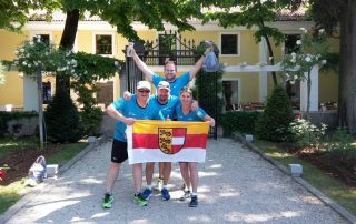 Vier Menschen/Team mit Kärnten Flagge