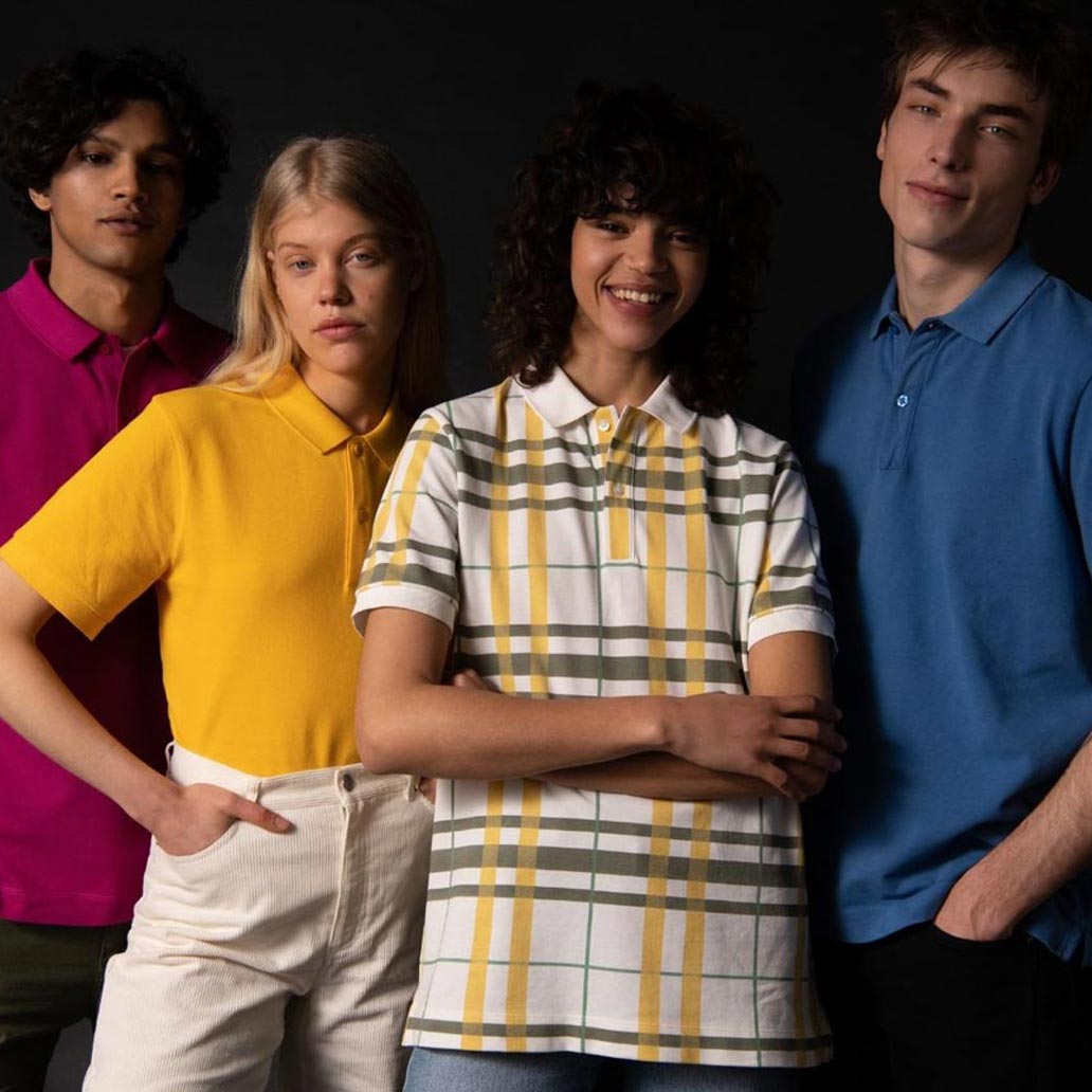 Vier Menschen stehen vor einem dunklen Hintergrund und tragen unterschiedlich farbige Poloshirts.